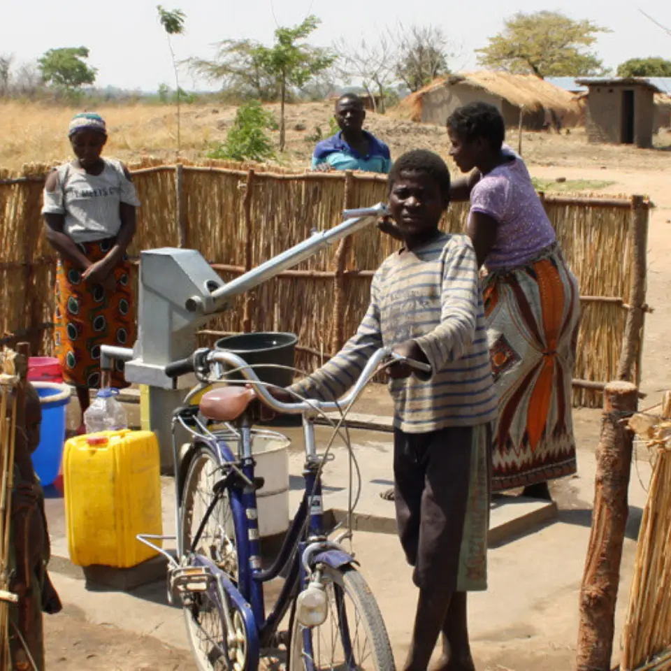 Gruppe aus Kindern, die sich Wasser an einem Brunnen in Malawi holen.