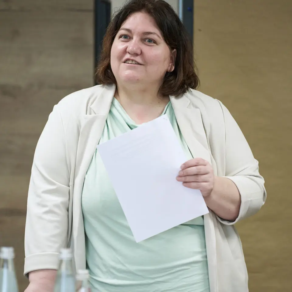 Frau hält Vortag mit weißem Zettel in der Hand