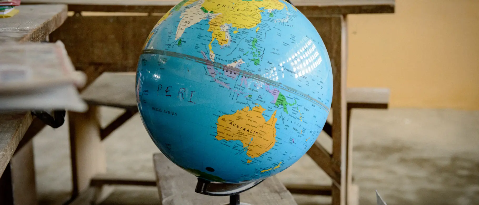 Ein Globus steht auf einer hölzernen Schulbank in einer Dorfschule in Togo, die durch das soziale Engagement von natureOffice im Rahmen von PROJECT TOGO unterstützt wird.