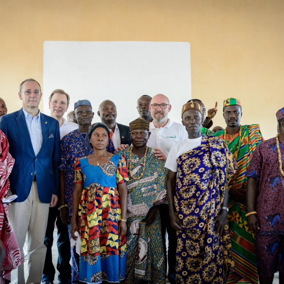 Gruppenfoto im Versammlungshaus in Togo: Andreas von natureOffice im Dialog mit lokalen Oberhäuptern und dem deutschen Botschafter zur Förderung der nachhaltigen Entwicklung.