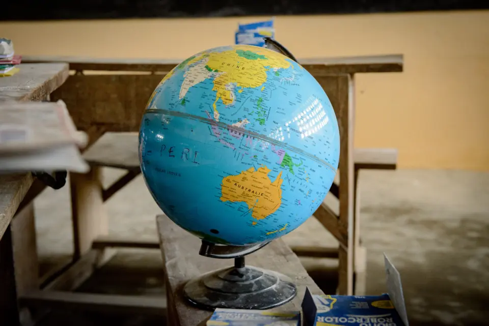 Ein Globus steht auf einer hölzernen Schulbank in einer Dorfschule in Togo, die durch das soziale Engagement von natureOffice im Rahmen von PROJECT TOGO unterstützt wird.