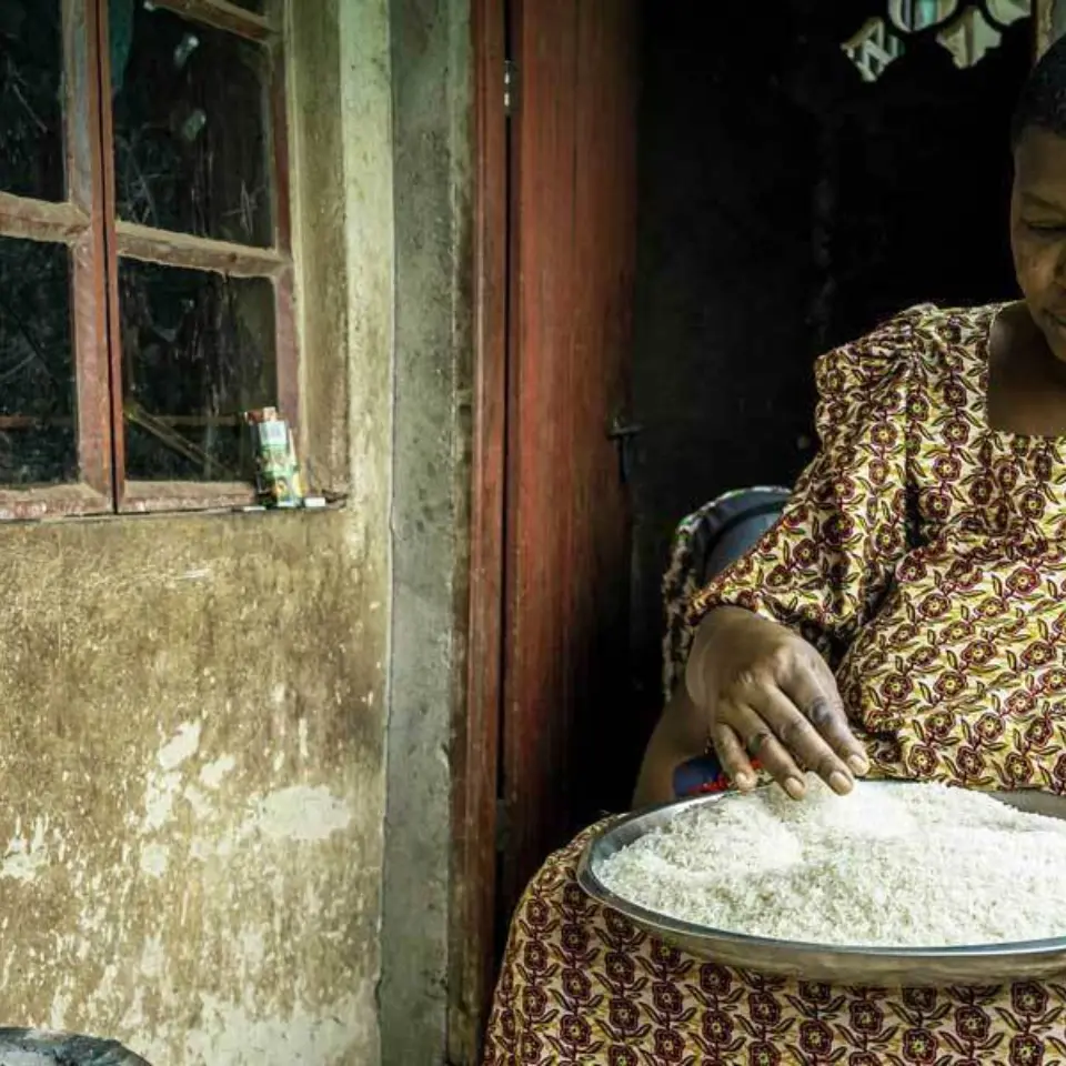 Ältere Frau sitzt vor Haus und Kocht