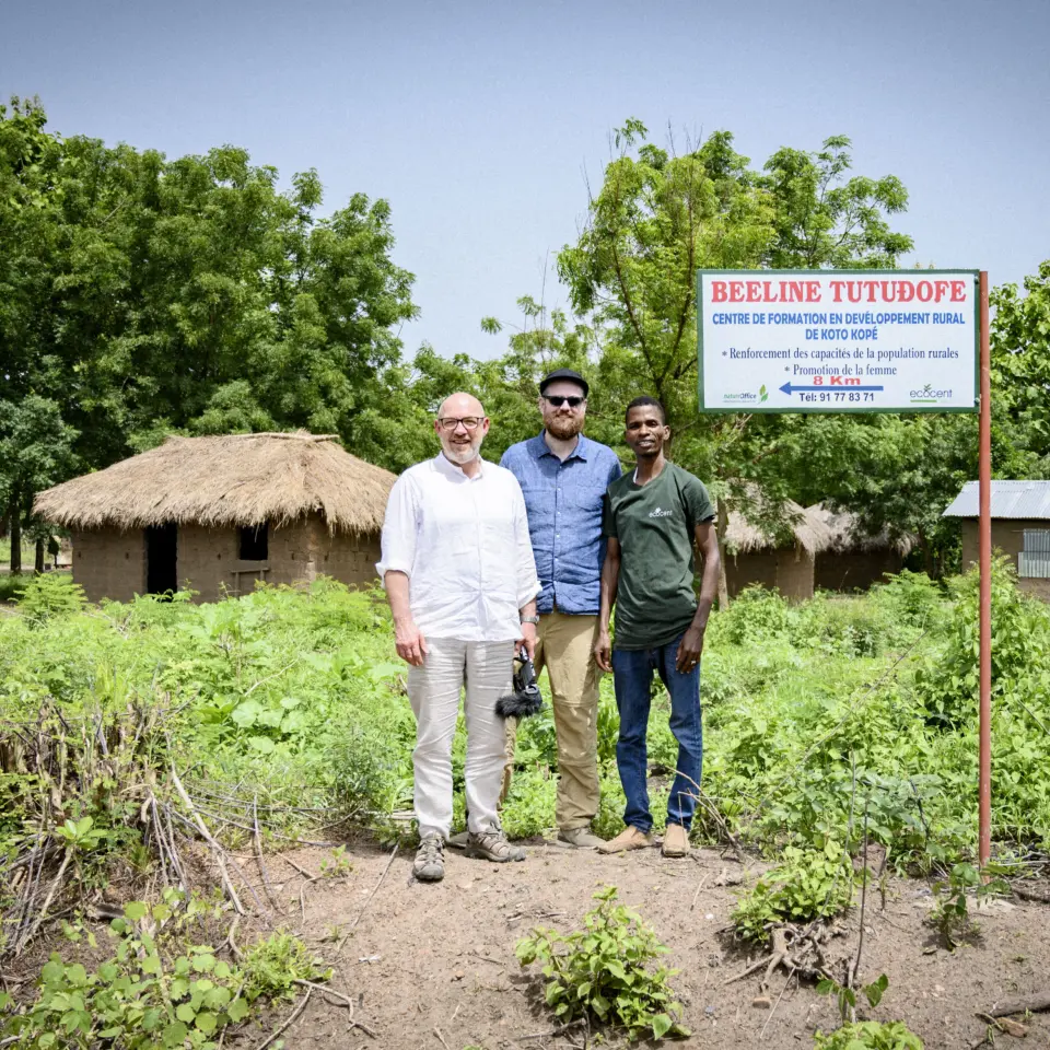 Two men pose together with a Togolese staff member in a village in Togo, where social projects such as the renovation of a school are being implemented as part of PROJECT TOGO.